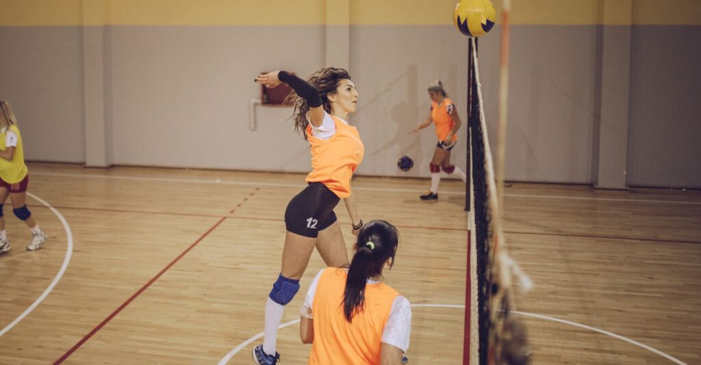 A woman hitting a volleyball spike.