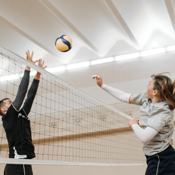 Two people playing volleyball near net