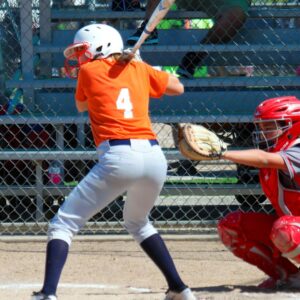 a softball player batting in an orange jersey