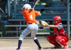 a softball player batting in an orange jersey